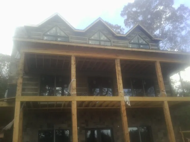 Dormers and porch framing on a large log home under construction — Roof Coating work by our crew in Pawnee