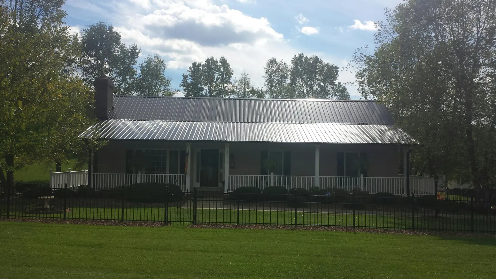 Gray metal roof on a brick ranch with a full width front porch — Gutter Guard Installation work by our crew in Pawnee