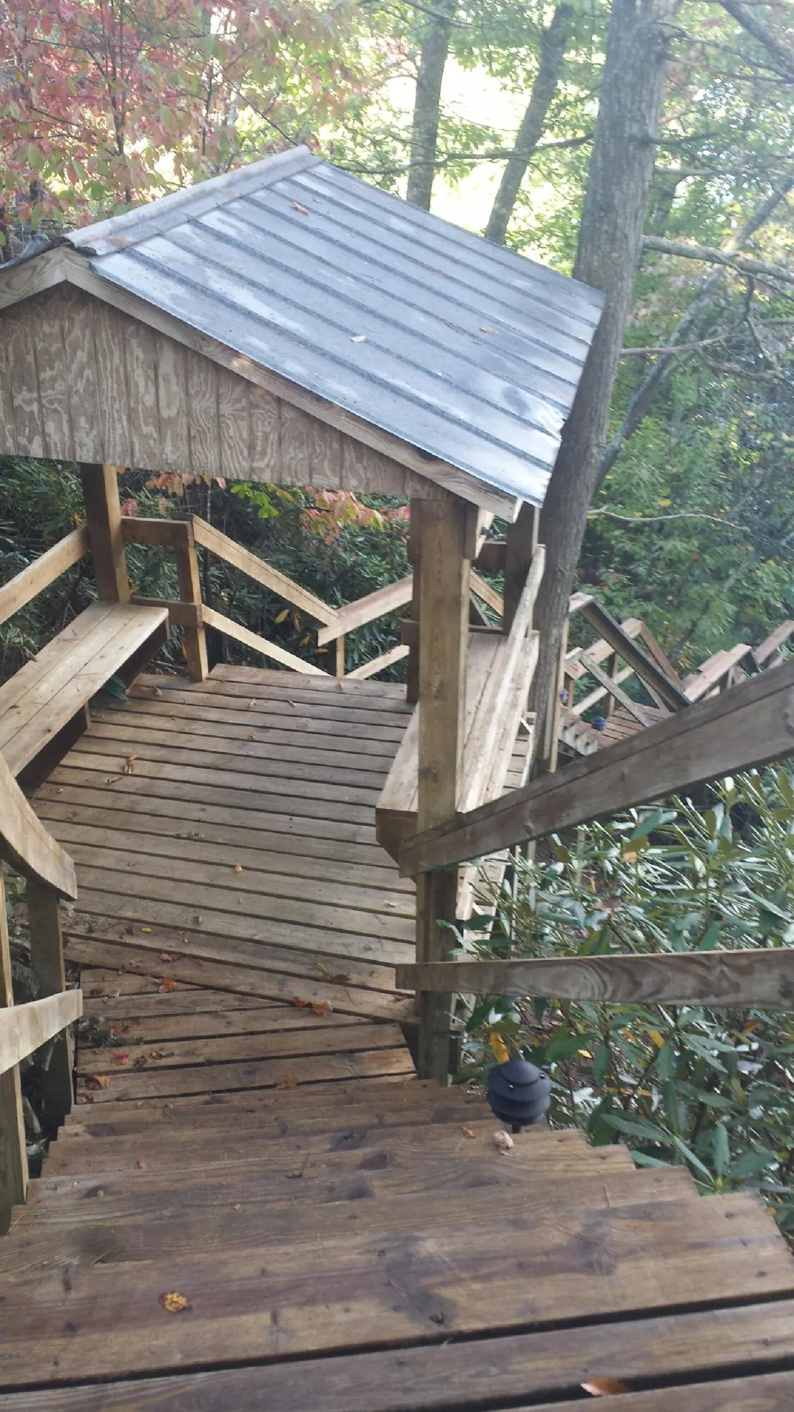 Metal roofed shelter over wooden steps on a wooded walkway — Skylight Repair & Installation work by our crew in Pawnee